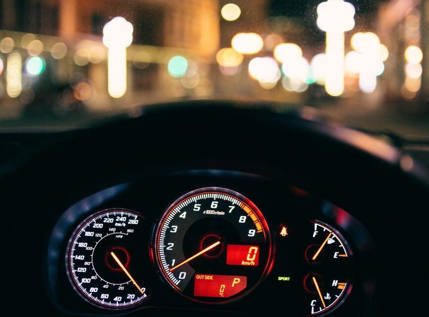 glowing dashboard of modern car driving in illuminated city street